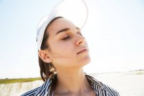 Woman in white visor posing on beach — Stock Photo