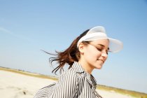 Donna in visiera bianca in posa sulla spiaggia — Foto stock
