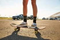 Frau steht mit Skateboard auf Parkplatz — Stockfoto