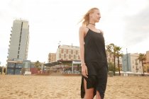 Vista basso angolo di bella donna in abito nero in piedi sulla spiaggia pubblica di Barcellona — Foto stock