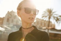 Retrato de mulher bonita em óculos de sol em pé na rua no dia ensolarado — Fotografia de Stock
