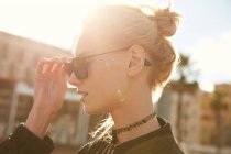 Side view of attractive woman wearing sunglasses on street at sunny day — Stock Photo