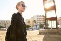 Низкий угол зрения на красивую женщину в солнцезащитных очках и сумке прогулки по общественному пляжу в Барселоне — стоковое фото