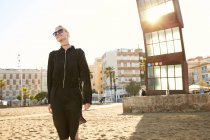 Beautiful smiling woman in sunglasses and bag walking on public beach in barcelona — Stock Photo