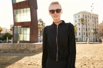 Attractive woman in sunglasses and bag walking on public beach in barcelona — Stock Photo