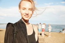 Portrait of cheerful woman looking at camera on beach in barcelona — Stock Photo