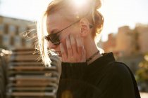 Vue latérale de la jeune femme en lunettes de soleil marchant sur la rue à Barcelone — Photo de stock