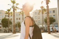 Side view of blonde young tourist with black bag standing on street in barcelona — Stock Photo