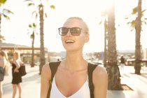 Mujer feliz en gafas de sol de pie en la calle en barcelona - foto de stock
