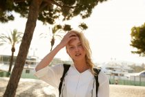 Attractive woman standing on quay in barcelona and touching hair — Stock Photo