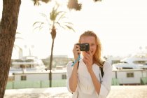 Smiling young traveler taking photo with digital camera on street in barcelona — Stock Photo
