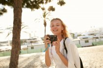Happy young tourist taking photo with digital camera on street in barcelona — Stock Photo