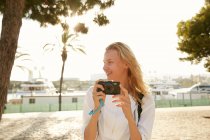 Smiling young traveler walking with camera on street in barcelona — Stock Photo