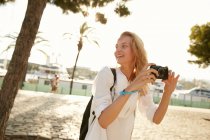 Smiling young tourist walking with camera on street in barcelona — Stock Photo