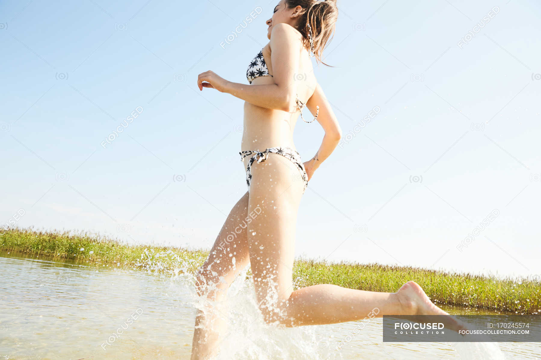 Woman In Swimsuit Running In Water Side View Joy Stock Photo