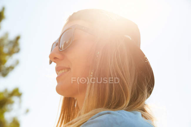Mujer rubia en gafas de sol y gorra snapback - foto de stock