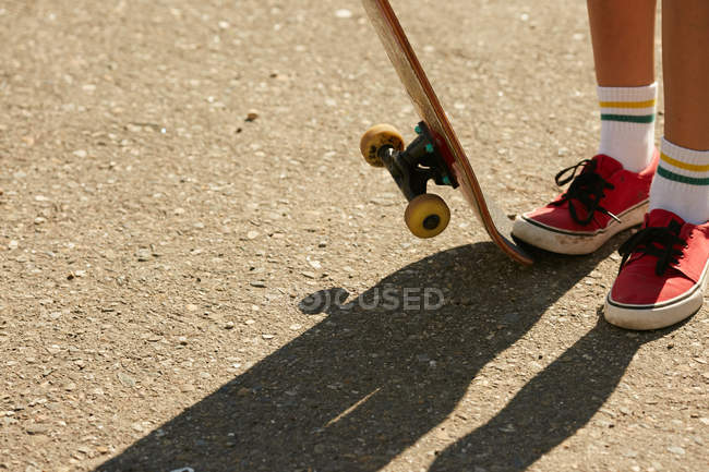 Pernas femininas em meias de joelho com skate — Fotografia de Stock