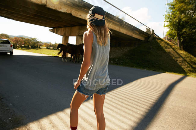 Mujer viendo caballos en camino al campo - foto de stock