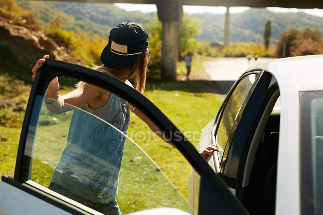 Frau steht neben offenem Auto — Stockfoto