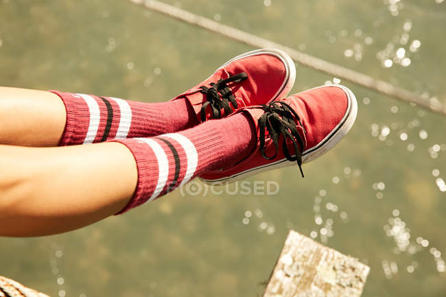 Pernas femininas em meias de joelho e tênis vermelho — Fotografia de Stock