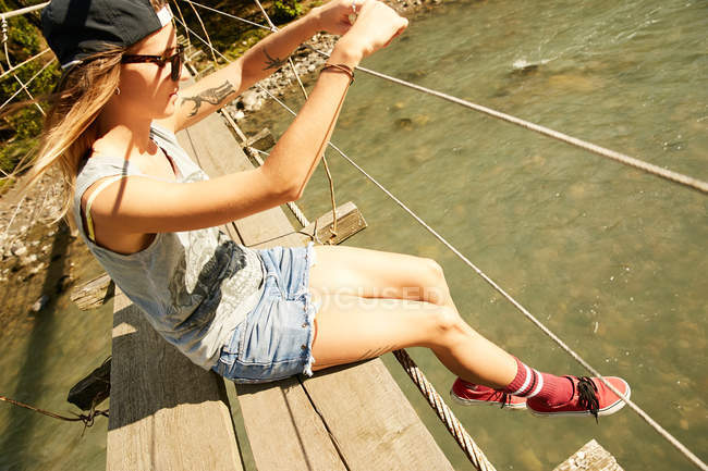 Woman sitting on hanging footbridge — Stock Photo