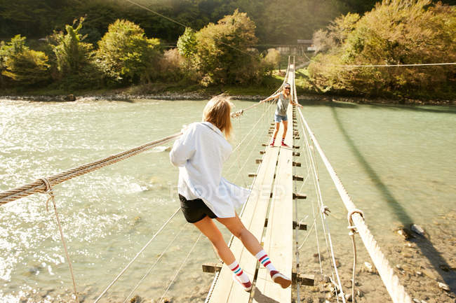 Women walking on hanging footbridge — Stock Photo