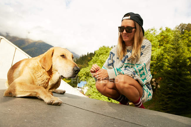 Жінка в светрі дивиться на собаку — стокове фото