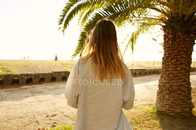 Жінка позує на пляжі з пальмою — стокове фото