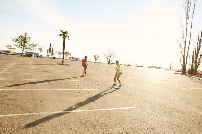 Donne che cavalcano su skateboard con zaini — Foto stock