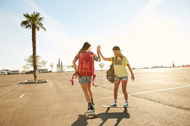 Women riding on skateboards with backpacks — Stock Photo