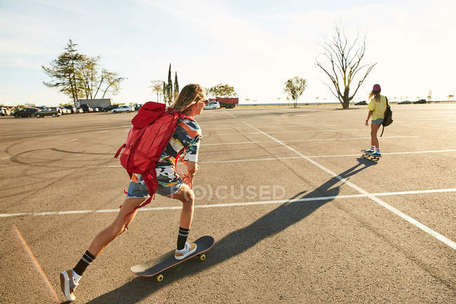 Frauen fahren auf Skateboards mit Rucksäcken — Stockfoto