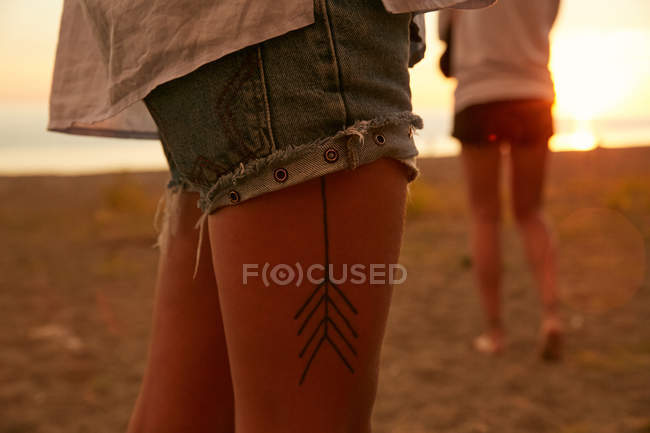 Donna gambe tatuate sulla spiaggia — Foto stock