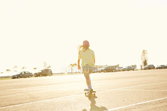 Woman riding on skateboard on parking lot — Stock Photo