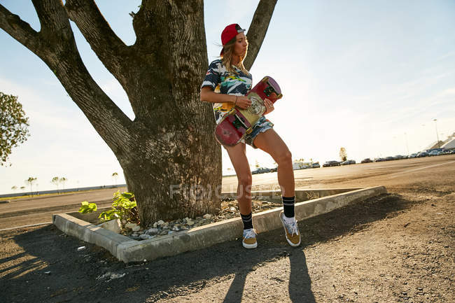 Frau hält Skateboard auf Parkplatz — Stockfoto