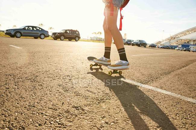 Mulher montando no skate no estacionamento — Fotografia de Stock