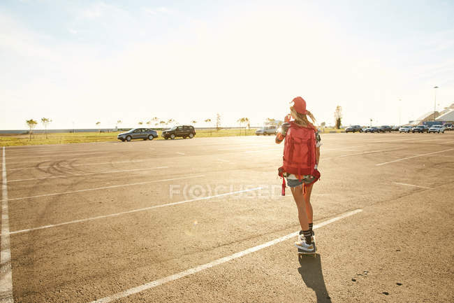 Woman riding on skateboard with backpack — Stock Photo