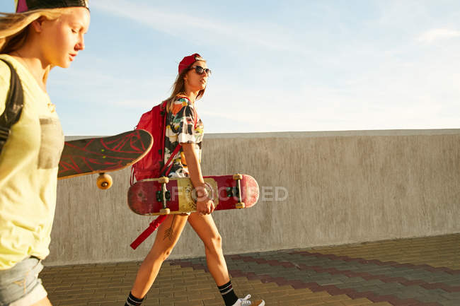 Женщины ходят с рюкзаками и скейтбордами — стоковое фото