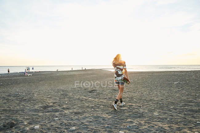 Woman holding skateboard on beach — Stock Photo