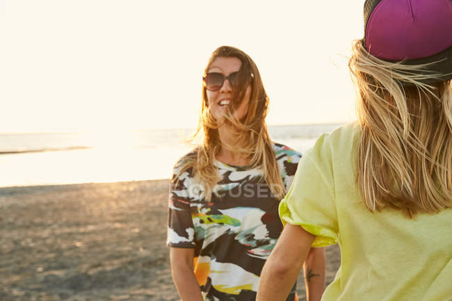 Mujeres divirtiéndose juntas en la playa ventosa - foto de stock