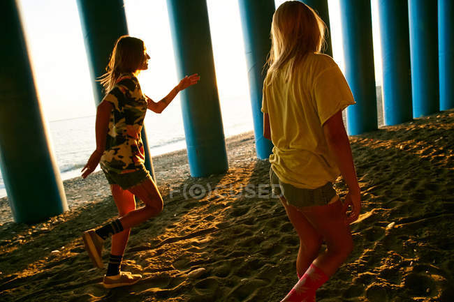 Femmes marchant sur la plage près des colonnes — Photo de stock