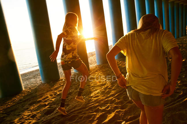 Women walking on beach near columns — Stock Photo