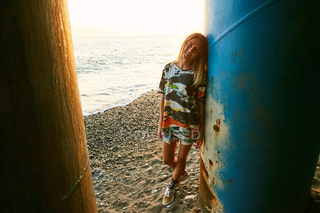 Woman standing near column on beach — Stock Photo