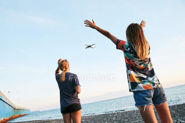 Mujeres mirando el avión en el cielo - foto de stock