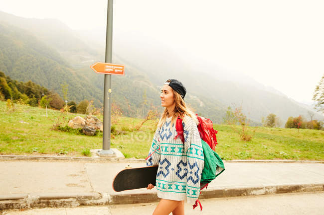 Donna che cammina con zaino e skateboard — Foto stock