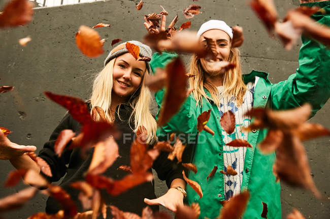 Amici femminili in posa con foglie autunnali — Foto stock
