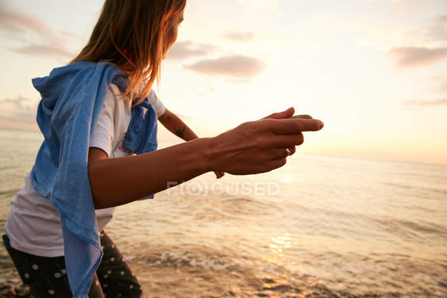 Girl throwing stone in water — Stock Photo