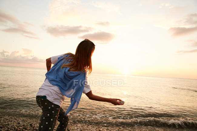 Chica lanzando piedra en el agua - foto de stock