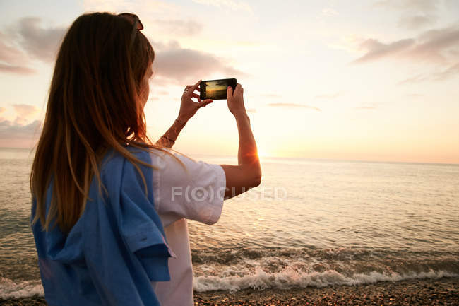 Fille prenant des photos de la mer — Photo de stock
