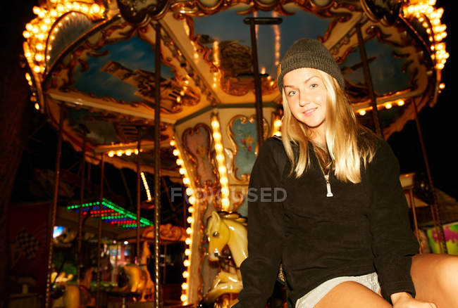 Menina sentada no parque de diversões carrossel — Fotografia de Stock