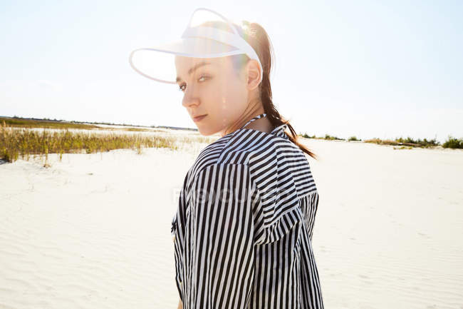 Femme en visière blanche posant sur la plage — Photo de stock